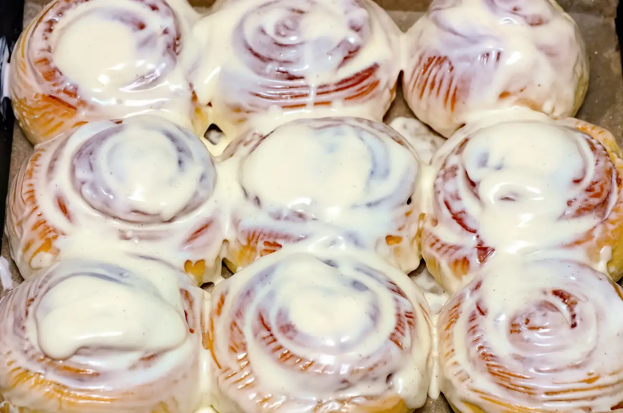 A pan of fresh cinnamon rolls under a thick layer of cream-cheese icing.