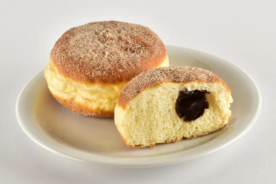 Cinnamon-sugar jelly doughnuts, one cut open to show the filling.