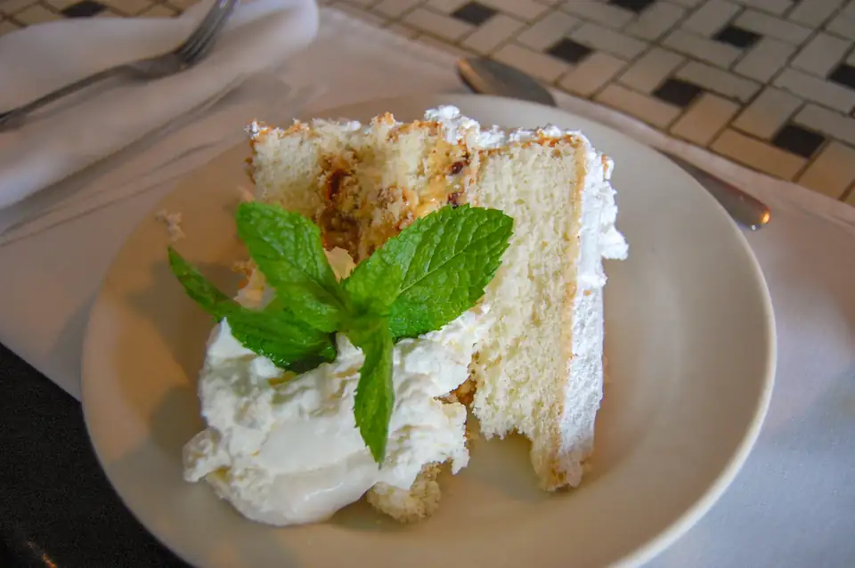 A slice of Lane cake, the Southern layer cake with a pecan-and-fruit filling, with whipped cream and mint.