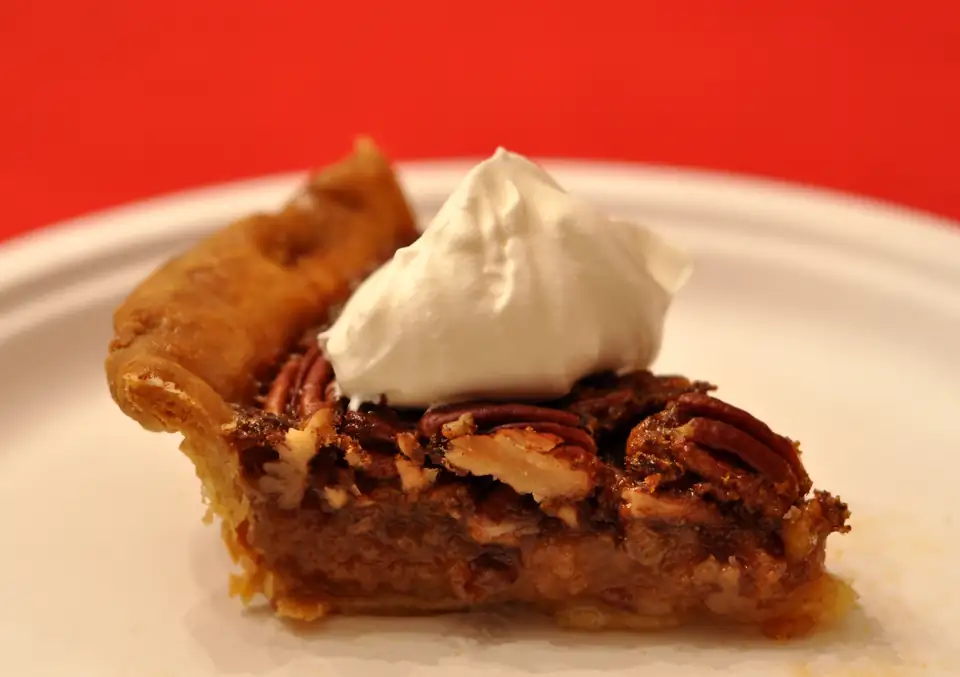 A slice of pecan pie topped with whipped cream.