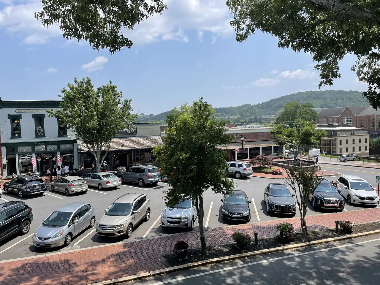 Looking down from the old courthouse across parked cars to a storefront advertising desserts, coffee and ice cream on Dahlonega's square, with wooded hills behind town.