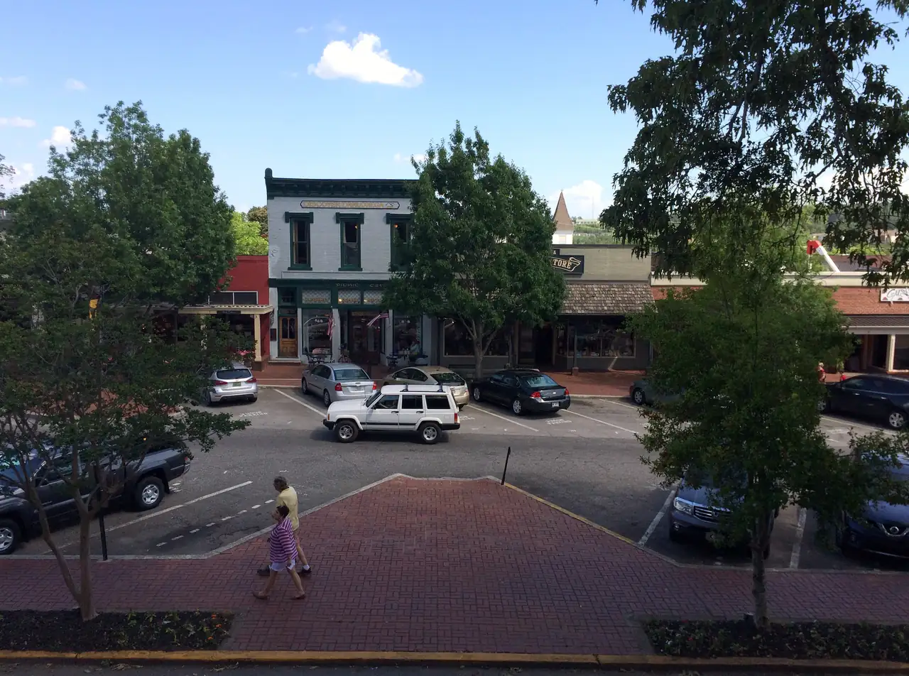 A summer afternoon view across Dahlonega's square to the white Picnic Cafe building and its neighbors, framed by shade trees.
